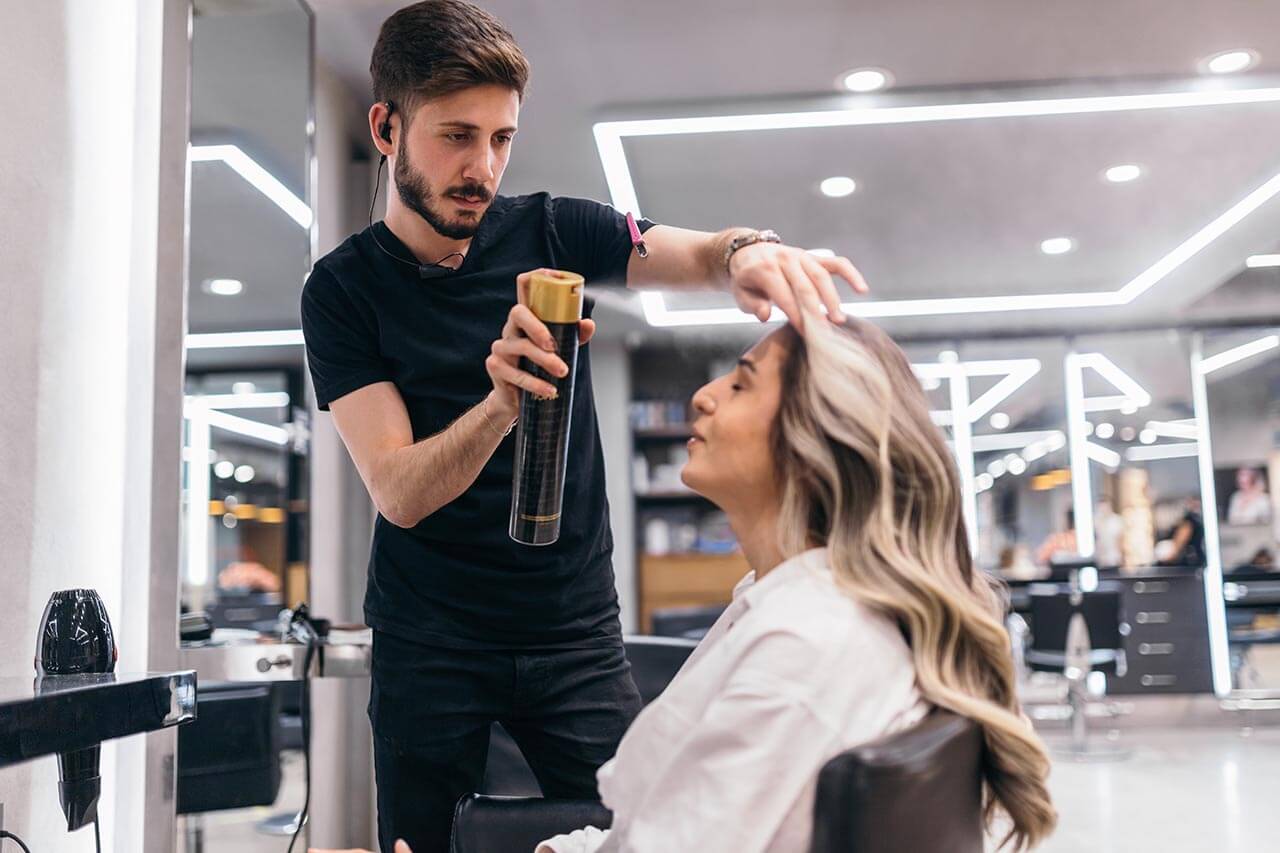 Hairdresser using hairspray on a customers hair