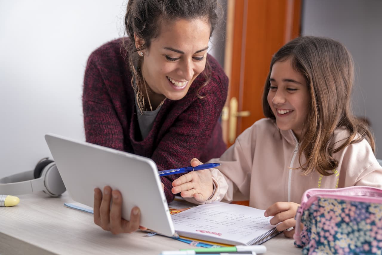 Tutor teaching a young person on a tablet