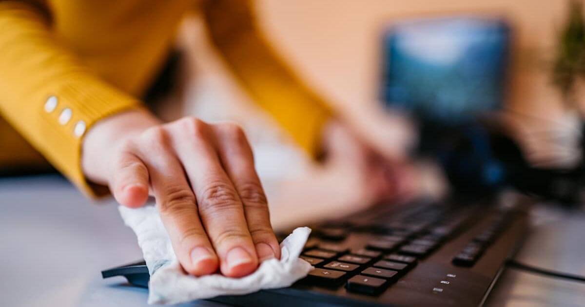 Close up of hands cleaning a computer keyboard
