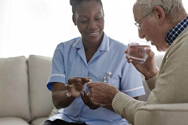 Care worker giving medication to a care home resident