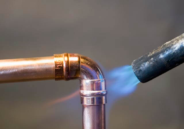 Blow torch heating a copper pipe bend