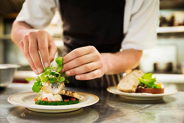 Chef plating up food in a kitchen