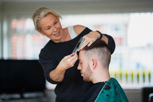 Hairdresser cutting clients hair at home