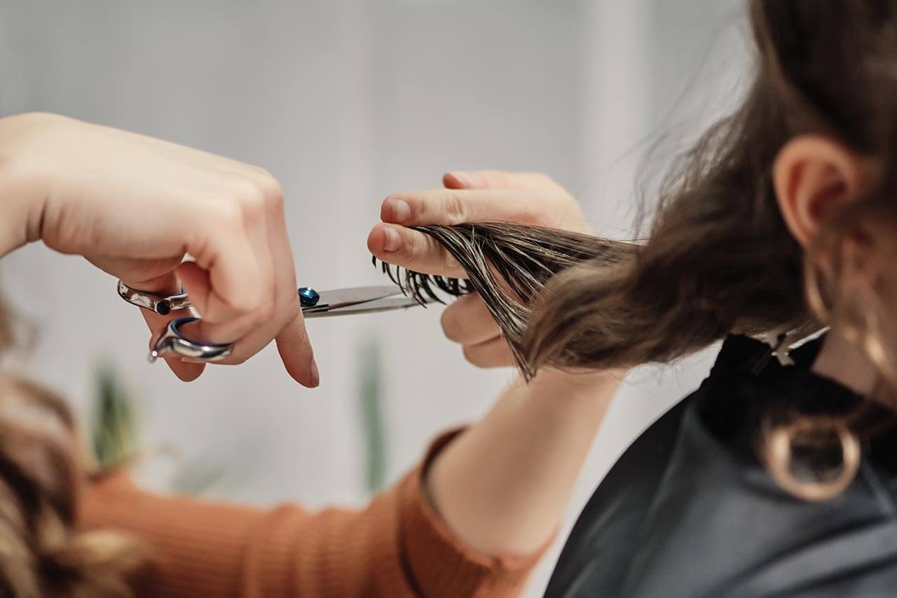 Hairdresser using scissors to cut hair