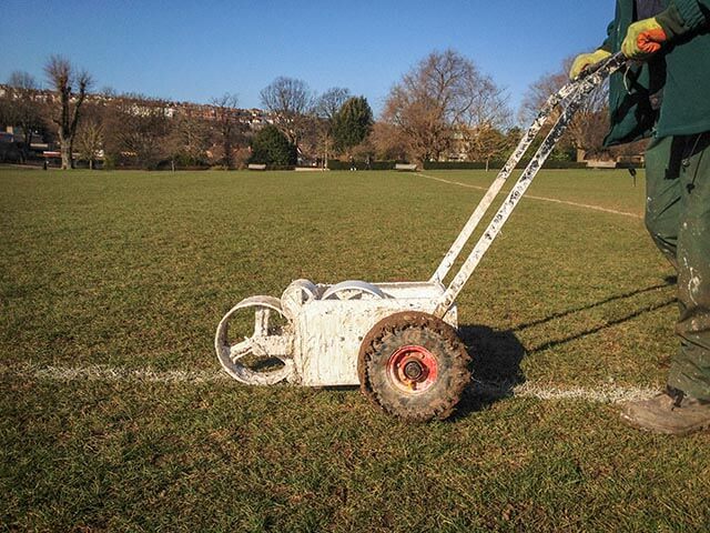 Groundskeeper painting lines on a sports pitch
